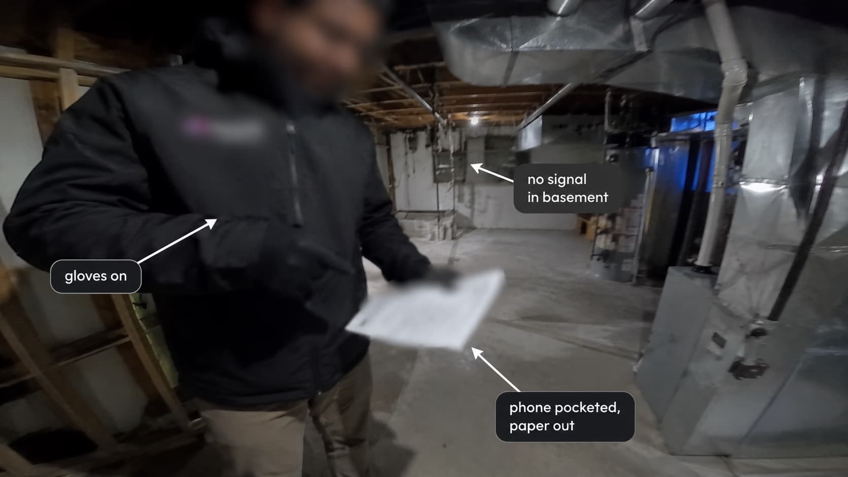 A GoPro frame from an inspection in a basement: the inspector has gloves on, his phone pocketed and a paper checklist out, and there is no signal down there